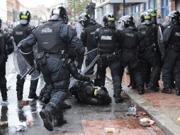 Un policía cae tras ser golpeado con un ladrillo durante las manifestaciones. AP /