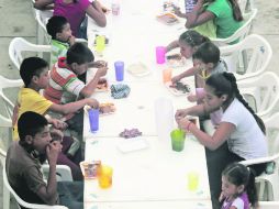 Desplazados de Tierra Caliente y la Costa Grande toman sus alimentos en una primaria de Tecpan de Galeana. AFP /