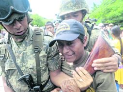 Desarmados. Militares forcejean con un miembro de la policía civil para quitarle su rifle. AP /