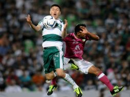 Oribe Peralta disputa el balón con Jose Juan Vazquez. Un apagón hizo que se detuviera el juego por diez minutos. AFP /