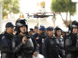 Un policía federal observa cómo se eleva el artefacto volador en miniatura. SUN /