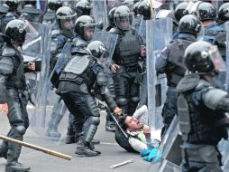 Policías someten a un joven durante el desalojo. En el operativo 11 personas resultaron lesionadas. AFP /