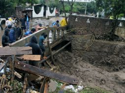 Pobladores de Chilpancingo tratan de reparar un puente destruido por las fuertes lluvias ocasionadas por ''Manuel''. AFP /