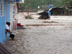 Una mujer saca agua de su casa en Guerrero, la entidad más afectada por los fenómenos meteorológicos. EFE /