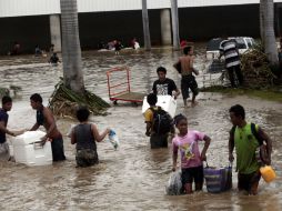 Pobladores de Guerrero toman sus pertenencias para cruzar una de las calles inundadas por el paso de ''Manuel'' e ''Ingrid''. AFP /