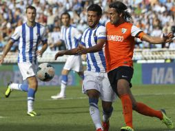 El centrocampista Carlos Vela lucha por defender el balón ante el defensa del Málaga, Sergio Sánchez. EFE /