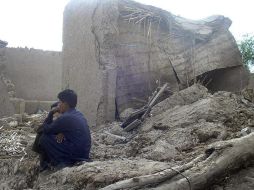 Varias personas permanecen junto a sus casas en ruinas tras el terremoto en Awaran, Pakistán. EFE /