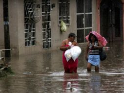 Un par de mujeres caminan por una de las calles inundadas en Acapulco. EFE /