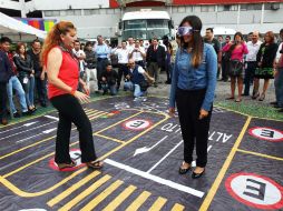 Veronica (d) avanza por la lona-maqueta con las gafas que simulan haber ingerido 12 cervezas.  /