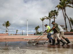 Un grupo de empleados de sanidad realizan una limpieza en el malecón de la entidad. ARCHIVO /