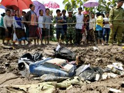 Lugareños observan una zona acotada donde estan varios objetos personales de los pasajeros y restos del fuselaje cerca del río Mekong. EFE /