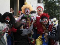 Varios payasos se acercan a una señora, ella acaricia a uno de ellos.  /