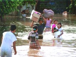 Familia traslada algunas pertenencias debido a que su hogar se encuentra inundado. ARCHIVO /