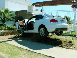 El coche derribó un árbol y quedó sobre una jardinera. ESPECIAL /
