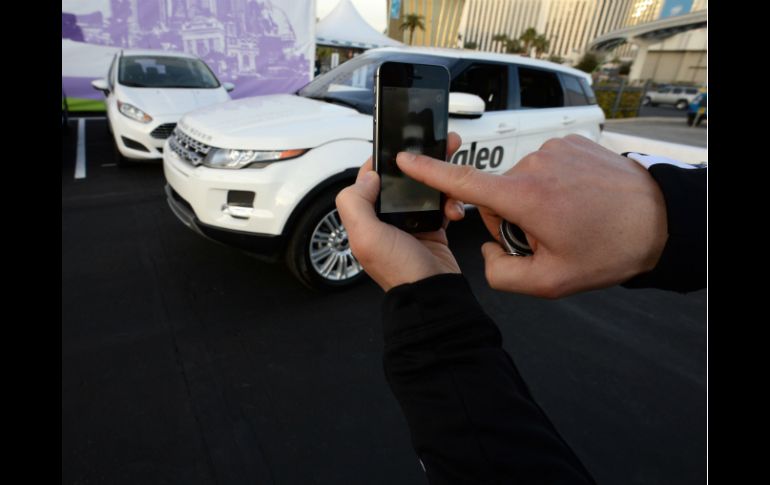Un hombre usa su smartphone para estacionar un auto. AFP /
