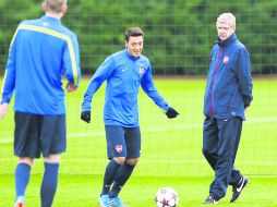 El alemán Mesut Özil se prepara bajo la mirada del técnico francés Arsene Wenger.  /