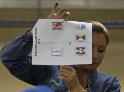 Una oficial muestra un voto durante el conteo de sufragios en el país. AP /