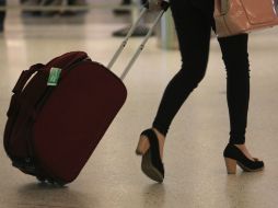Una mujer camina con su maleta por un aeropuerto. ARCHIVO /