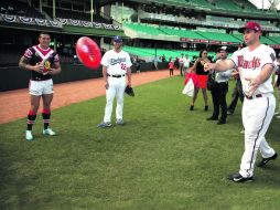 Paul Goldschmidt lanza un ovoide de rugby, mientras el abridor de los Dodgers, Clayton Kershaw (centro), lo observa.  /