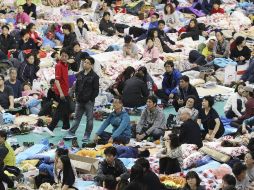 Familiares de las 268 personas que siguen desaparecidas permanecen en un gimnasio de escuela a la espera de más información. AP /