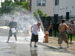 Varias personas juegan con el agua que sale de un hidrante roto. ARCHIVO /