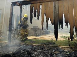 Un bombero trata de sofocar el fuego a las afueras de una casa en la ciudad de Carlsbad. AP /
