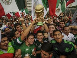 Aficionados sostienen una réplica de la Copa del Mundo.  /