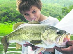 Este pequeño pescador contempla con admiración a su gordinflón trofeo.  /