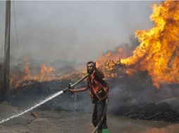 Un hombre palestino trata de extinguir el fuego que ocasionó un ataque aéreo israelí cerca de la ciudad de Gaza. AFP /