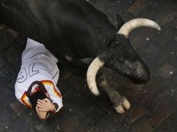 Un mozo se cubre ante la embestida de uno de los toros. AP /