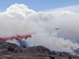 Un avión arroja agua sobre las áreas siniestradas para controlar el incendio. AP /