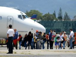Niños junto con sus madres caminan por la pista de la Fuerza Aérea Guatemalteca tras arribar desde EU. AFP /