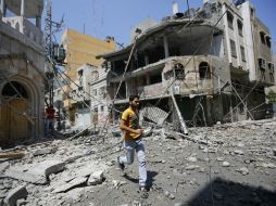 Un hombre palestino corre entre unos edificios destruídos para ponerse a cubierto durante un ataque aéreo israelí sobre Gaza. EFE /