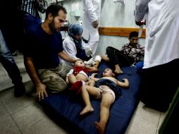 Un hombre palestino cuida a un par de niños en una sala de emergencia de un hospital, luego del bombardeo a una escuela. AP /
