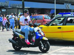 INFRAGANTI. Un motociclista sin casco, con audífonos y viendo el celular transita por el cruce de Alcalde y Juárez.  /