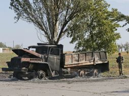 Un camión totalmente destruido arde junto a la carretera y varios edificios cercanos presentan daños. EFE /