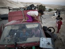 Niños israelíes juegan en los restos de un automóvil en el desierto de Judea. EFE  A. Sultan  /