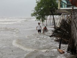 Dos hombres caminan por una playa inundada por fuertes olas propiciadas por la tormenta 'Polo'. EFE  F. Meza  /