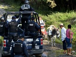 Elementos de seguridad federales pasan cerca de algunos vecinos de Iguala. AFP / Y. Cortez