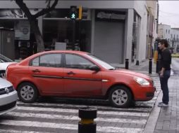 Se ve como el joven se planta frente al automóvil rojo en una de las calles principales del Centro de Guadalajara. FACEBOOK / El poder es Nuestro