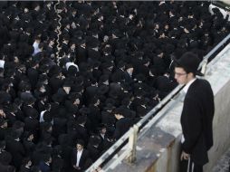 Un judío ultraortodoxo observa a cientos de participantes en el funeral de una de las víctimas del ataque terrorista. EFE / A. Sultan