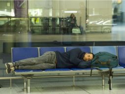 Un pasajero descansa en el aeropuerto de Gatwick, tras la cancelación de vuelos por una falla técnica que ya ha sido reparada. AFP / J. Tallis