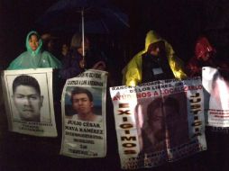En medio de la lluvia, los padres y familiares portan cartulinas con las fotografías de sus hijos. TWITTER / @Tlachinollan