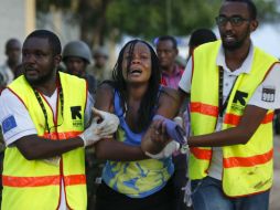 Dos sanitarios ayudan a una mujer que ha escapado de la Universidad de Garissa. EFE / D. Kurokawa