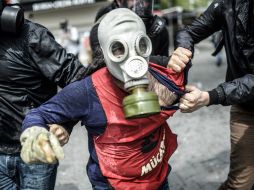 La policía turca detienen a un hombre que protesta cubriendo su rostro con una máscara de gas durante el 1 de mayo. AFP / B. Kilic