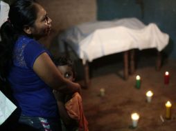 Una mujer, junto a un niño, llora cerca de los cuerpos de tres víctimas luego del enfrentamiento de Xolapa. AFP / P. Pardo