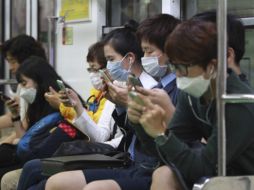 Atentos. Pasajeros usan máscaras como medida de precaución contra el MERS y se informan en un tren subterráneo en Seúl. AP /