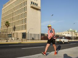 Un hombre, que lleva una playera con la bandera estadounidense, camina a las afueras de la Embajada de EU en La Habana. AFP / A. Roque