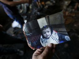 Un familiar muestra una fotografía de Ali Dawabsha, bebé que murió en su casa en un incendio provocado por extremistas israelíes. EFE / A. Badarneh
