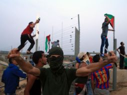 Un encapuchado hace un gesto retador con armas blancas en los puños, en la línea divisoria entre Israel y Gaza. AFP / M. Abed